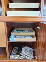 Cabinet interior showing two trays of loose stamps and album pages below