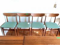 Front view of all four teak dining chairs aligned