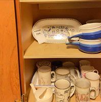 Cabinet view showing platter, stacking bowls, assorted mugs and gravy boat