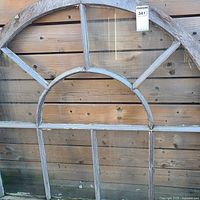 Full view of arched wood window showing frame and missing panes