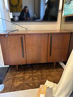 Front view of wooden console cabinet under wall-mounted TV