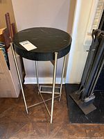 Front view of black marble top table on brass frame