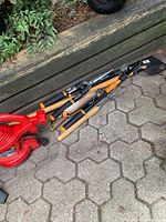 Toro red electric blower and Fiskars loppers, shears and pruner grouped on patio