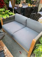 Loveseat with grey cushions showing wood frame and rope sides