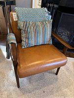 Front view of leather chair with pillow, throw and fabric visible