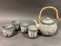 Teapot and four cups arranged together showing overall design and condition