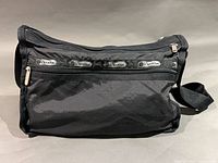 Front view showing overall shape, top-zip closure, adjustable strap