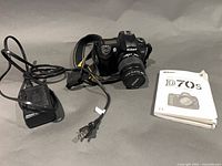 Camera with attached lens, charger with cord, manual