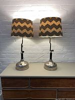 Both lamps with shades illuminated on dresser against brick wall