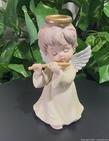 Front view of porcelain angel figurine with flute, halo and wings visible
