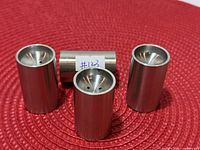 four stainless steel shakers upright on red mat