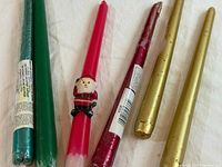 All six taper candles laid out: teal, green, red Santa, red metallic, two gold