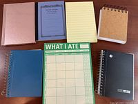 Seven assorted notebooks and journals laid out on table