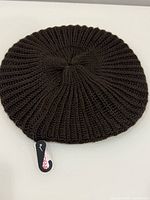 Top view of dark brown ribbed knit beret hat with Ardene tag attached