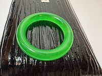 Top view of translucent green bangle resting on black surface