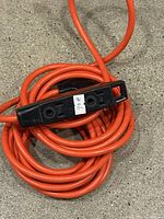 Coiled orange extension cord showing black dual-outlet receptacle