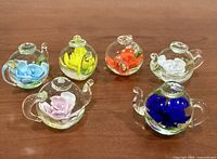 All six miniature glass teapots showing diverse internal flower colors