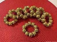 Group of beaded gold-tone napkin rings on red mat