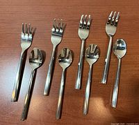 All 8 utensils arranged on wood surface, showing fronts