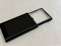 Magnifier partially extended showing clear rectangular lens and black housing