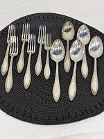 Full grouping of 6 forks and 5 spoons on mat