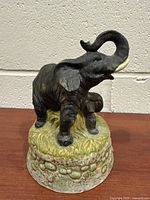 Front view of adult elephant with raised trunk on textured base
