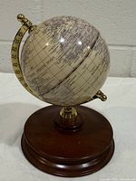 Front view showing globe, brass-tone meridian, wood base