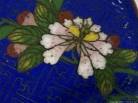 Close view of floral cloisonné motif on blue enamel surface
