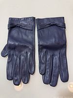 Full view of both gloves laid flat showing front side and bow detail