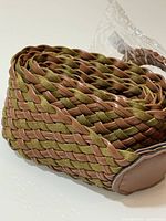 Coiled belt showing brown faux leather and olive green fabric weave