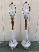 Full view of both lamps showing ceramic bases, wood necks, harps and bulbs