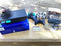 PS2 console, box, controllers, games, cables, memory cards displayed on table