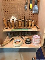 Overall shot showing chisels, scrapers, trowel, utility knife, and tape rolls on shelves