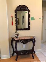 Console table with marble top, mirror above, bonsai and tassel visible