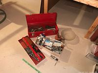 Overall lot on floor showing toolbox, shade, oil can, box of electrical parts