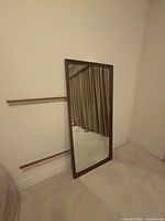 Full view of freestanding rectangular mirror with wood frame and attached dresser supports