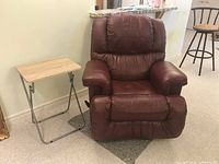 Front view of burgundy swivel recliner next to folding TV tray table