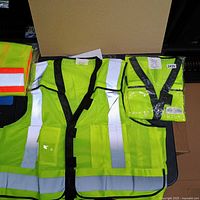Three lime safety vests, two packaged, one loose, showing reflective strips and mesh