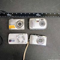 Group shot of four compact digital cameras with ruler for scale