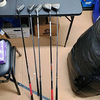 All five clubs leaning against table, showing full length and clubheads