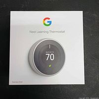 Retail box front showing Google Nest Learning Thermostat branding and stainless steel finish