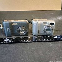 Both Nikon Coolpix cameras front view with ruler for scale