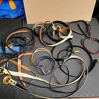 Overview of tangled group of belts showing variety of colours and buckles