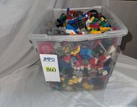 Full view of clear bin packed with mixed LEGO pieces, lot label visible