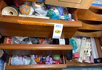 Open drawer showing mixed yarn balls, crochet cotton, small craft items