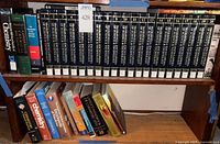 Shelved set of encyclopaedia volumes with additional textbooks on lower shelf