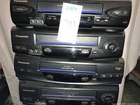 Front view of four stacked Panasonic VCRs showing model styling and controls