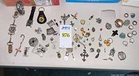 Full lot overview on tabletop showing pendants, rings, watches, bracelet and comb