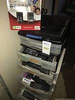 Stack of drawers filled with numerous remote controls and boxed remotes on top
