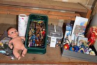 Full lot view showing baby doll, LEGO case, Playmobil bin, tray with Bionicle and tops